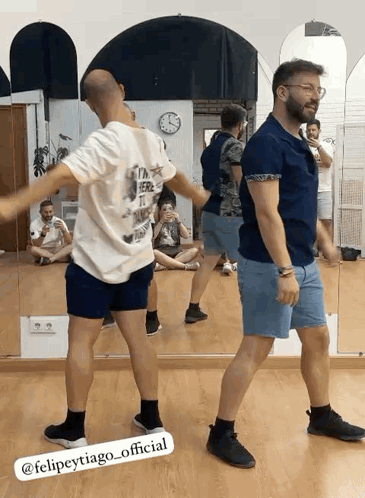 a group of men are dancing in front of a mirror in a dance studio