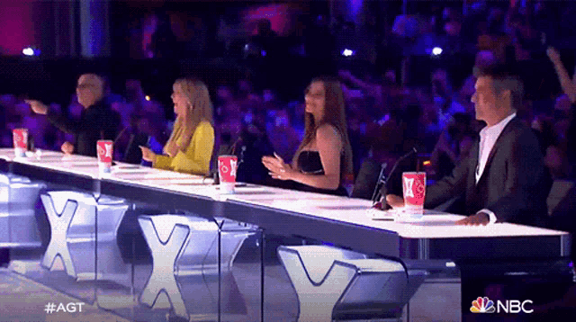 a group of people sitting at a table with a sign that says nbc on it