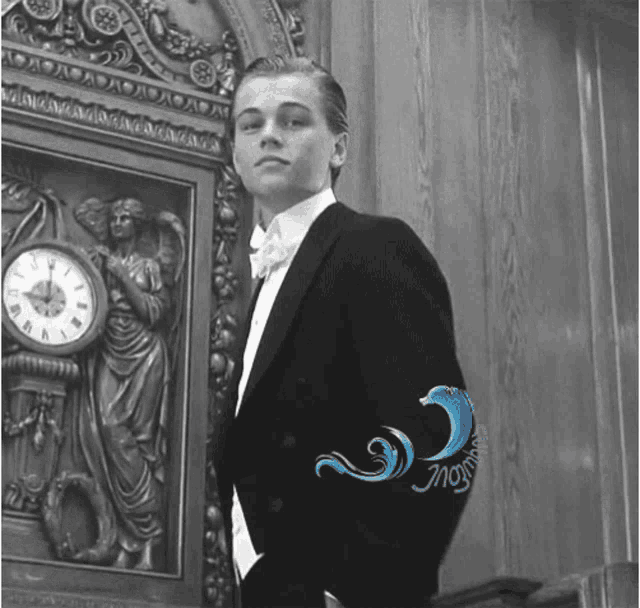 a man in a tuxedo is standing in front of a clock that shows the time as 4:20