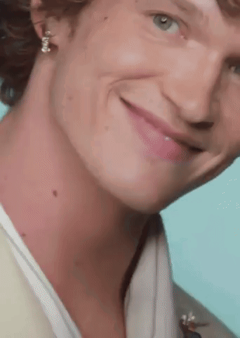 a close up of a man 's face with a smile on his face and earrings .