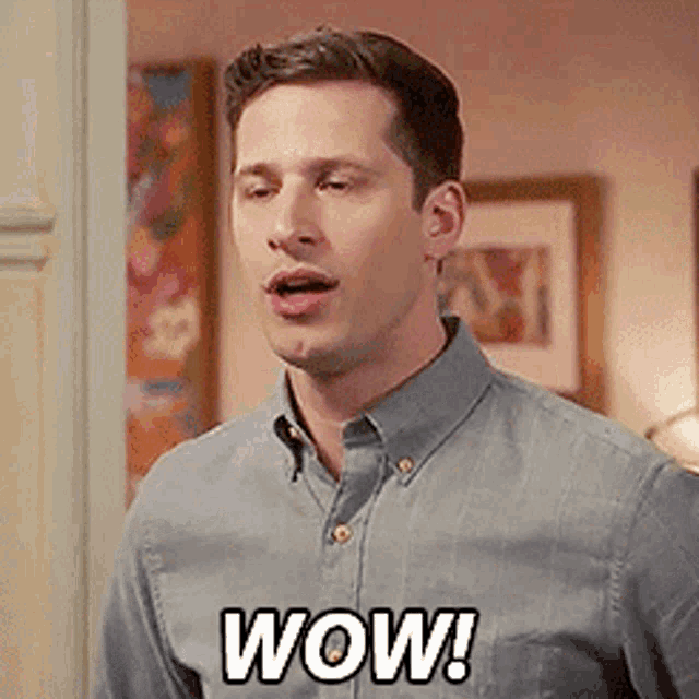 a man in a blue shirt is saying wow in a room .