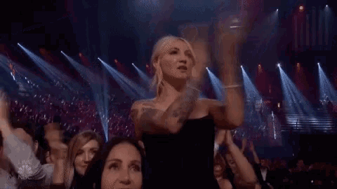 a woman is dancing on a stage in front of a crowd at a concert .