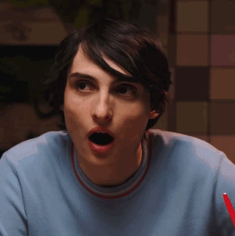 Finn Wolfhard looks forward with his mouth open in surprise.