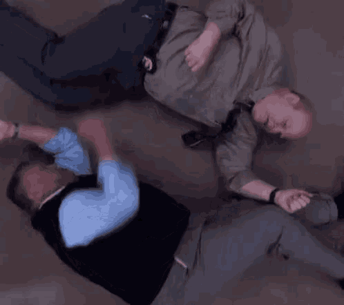 two men are laying on the floor fighting .