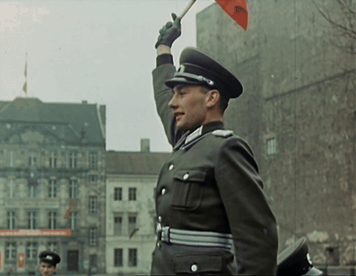 a man in a military uniform holds up a red flag with the letters rsc on it