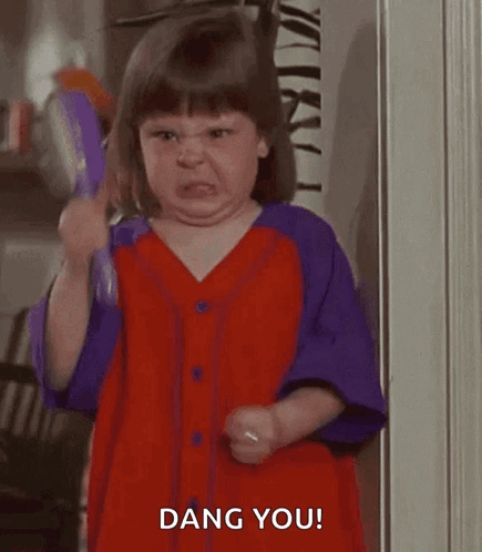 A child in a purple outfit angrily points a brush or stick.