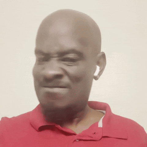 a bald man wearing a red shirt and ear buds makes a funny face