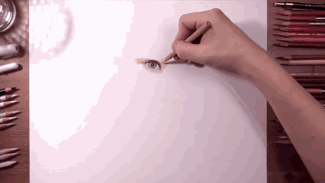 a person is drawing a blue eye on a piece of paper with colored pencils