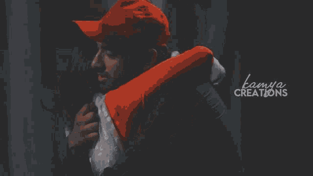 a man in a red hat is hugging a woman in a white dress with the words lamya creations written on the bottom