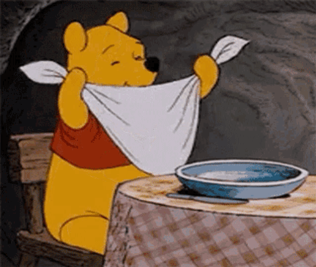 Winnie the Pooh lifts a napkin at a dinner table.