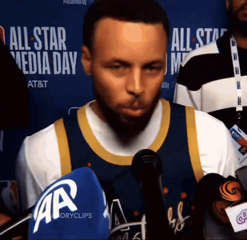 a basketball player stands in front of microphones at an all star media day