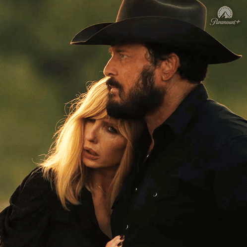 a man in a cowboy hat is hugging a woman in front of a paramount+ logo