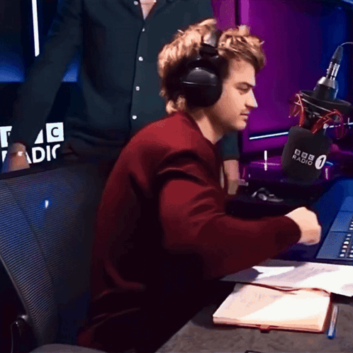 a man wearing headphones sits in front of a microphone that says bbc radio 0