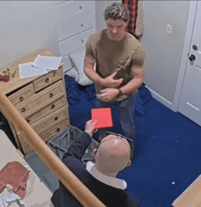 a bald man is holding a red card in his hand