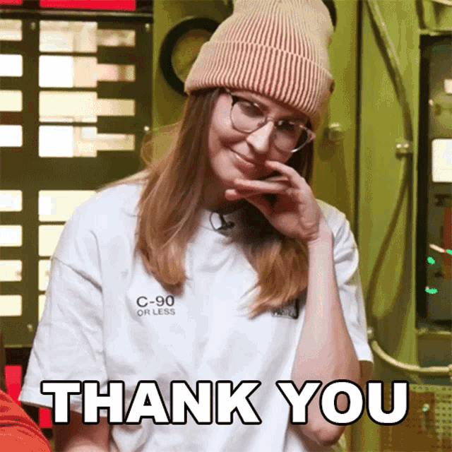 a woman wearing a beanie and glasses is smiling and says thank you