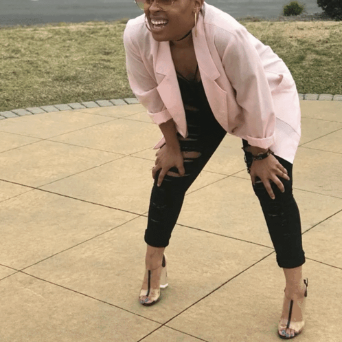 A woman bends forward with her hands on her knees and squints skeptically.
