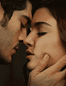 A couple kisses passionately while one person cups the other's face.
