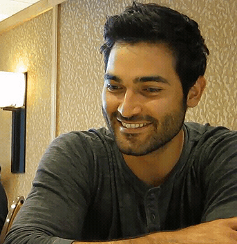 a man with a beard is smiling and wearing a gray shirt