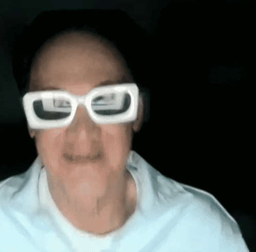 a man wearing white glasses and a white shirt is making a funny face