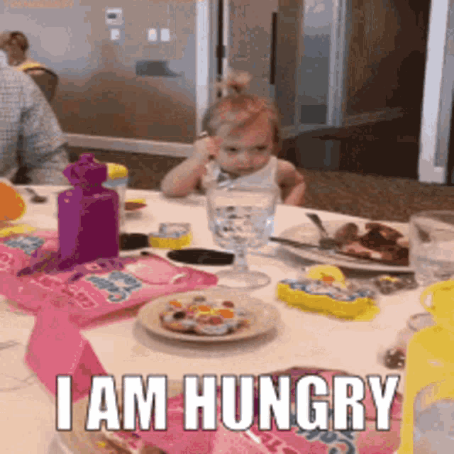 A child sits at a table with food, captioned “I AM HUNGRY.”