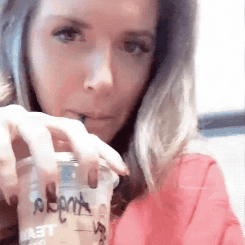 a woman is drinking from a plastic cup that says ' a ' on it