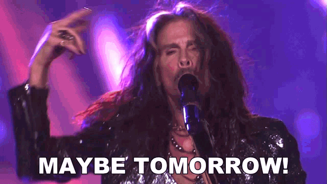 a man with long hair singing into a microphone with the words maybe tomorrow behind him