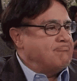 a man in a suit and tie is wearing glasses and making a funny face .