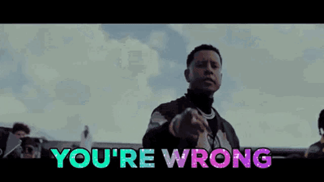 a man is pointing at the camera and the words you 're wrong are behind him .