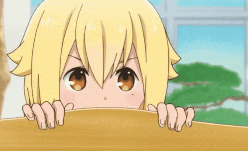 A blond anime character peeks over a desk with hands visible.