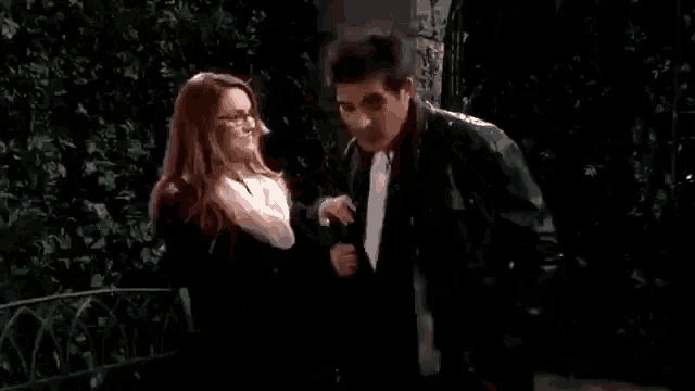 a man and a woman are standing next to each other and the woman is putting a jacket on the man 's jacket .