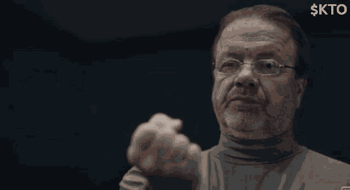 A man points toward the camera in a dark scene.