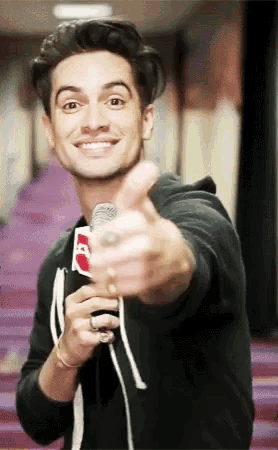 a man is holding a microphone and giving a thumbs up