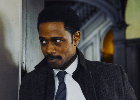 a man in a suit and tie is leaning against a door