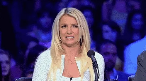 A blonde woman makes an awkward, uncomfortable smile onstage.