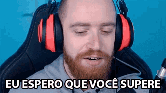 a man with a beard wearing headphones and a microphone is sitting in a chair .