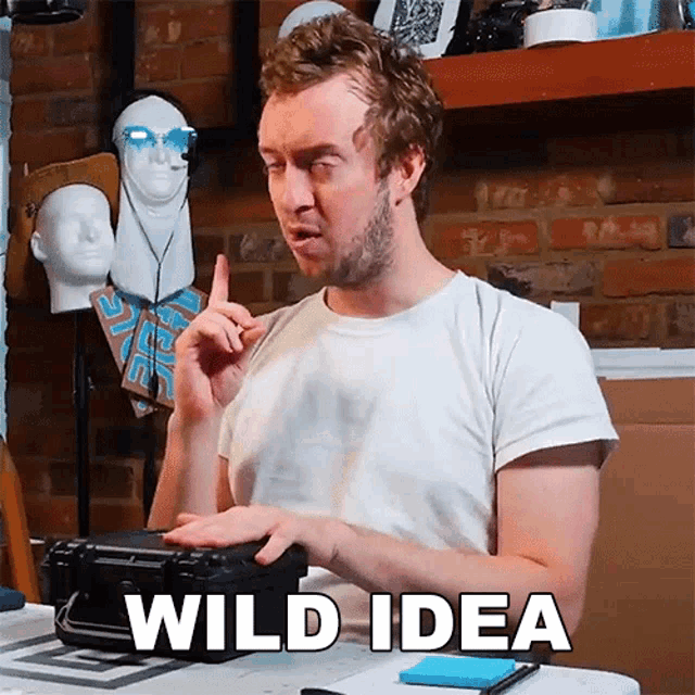 a man in a white shirt is sitting at a table with a case in front of him and says wild idea