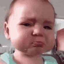 A baby makes a pouty, tearful expression in a close-up shot.