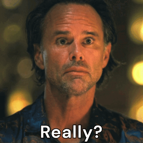 Walton Goggins looks forward with a wary, surprised expression.