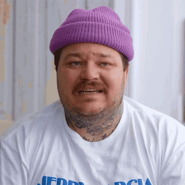 a man wearing a purple beanie and a white shirt that says freddy