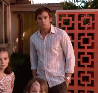 Dexter Morgan stands in a doorway with a confused, open-handed posture.