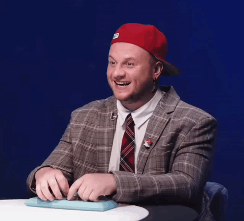 a man wearing a plaid suit and a red hat with the letter d on it is smiling