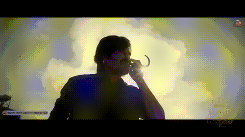 a man is talking on a cell phone and drinking from a glass .