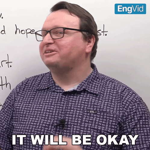 a man with glasses says it will be okay in front of a white board