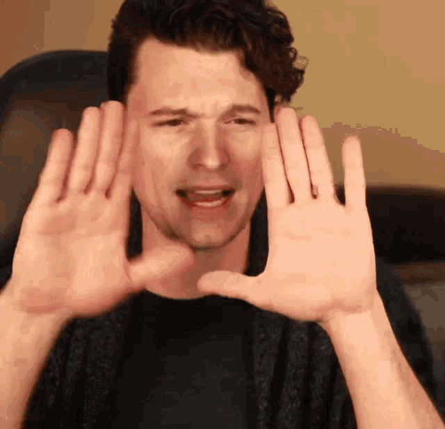 a man is making a face with his hands in front of his face