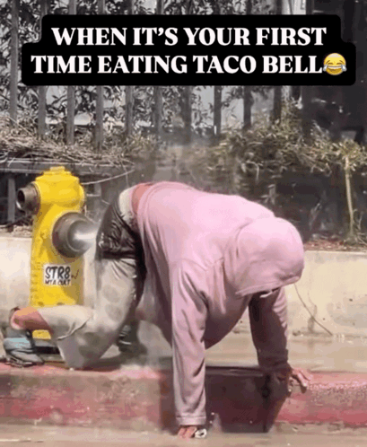 a man crawling on the sidewalk next to a yellow fire hydrant that says str8
