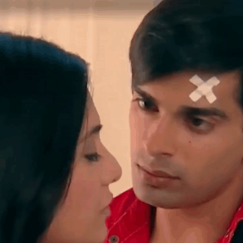 a man and a woman are looking into each other 's eyes with a bandage on their foreheads .