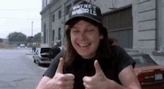 a man wearing a wayne 's world hat is giving a thumbs up .