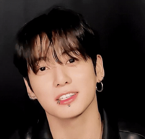 Jungkook smiles softly in a close-up portrait.