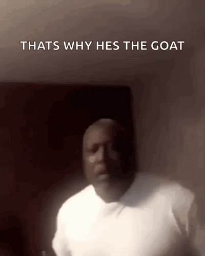 A man in a dim room is captioned “THATS WHY HES THE GOAT.”