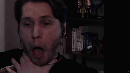 a man wearing headphones looks surprised in front of a bookshelf with a box that says ' reebok ' on it